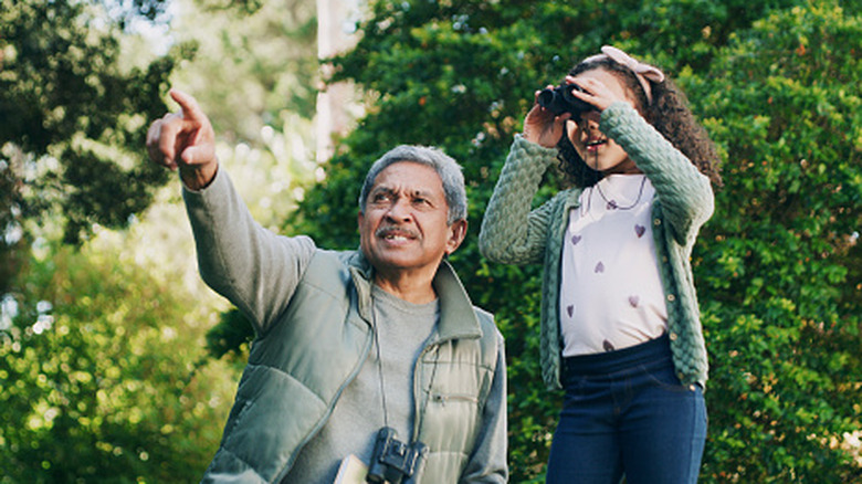 Father and granddaughter bird watching in nature