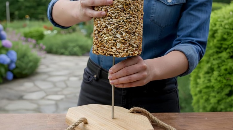 A person slides a seed cylinder on a Flockin' Cylinder Bird Feeder