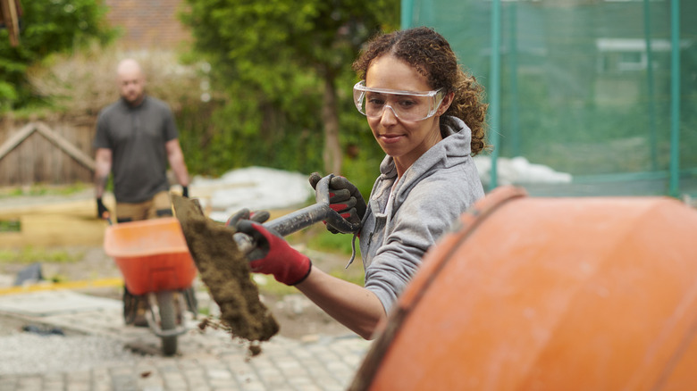 A woman mixing concrete for a garden project