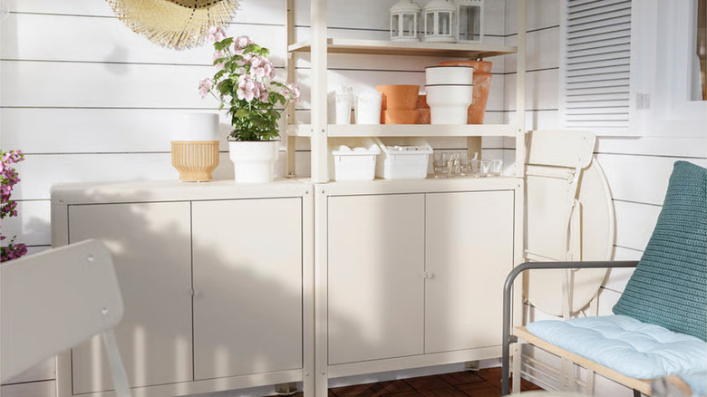 Two beige KOLBJORN cabinets, one with a shelving unit above holding plant pots and small items.