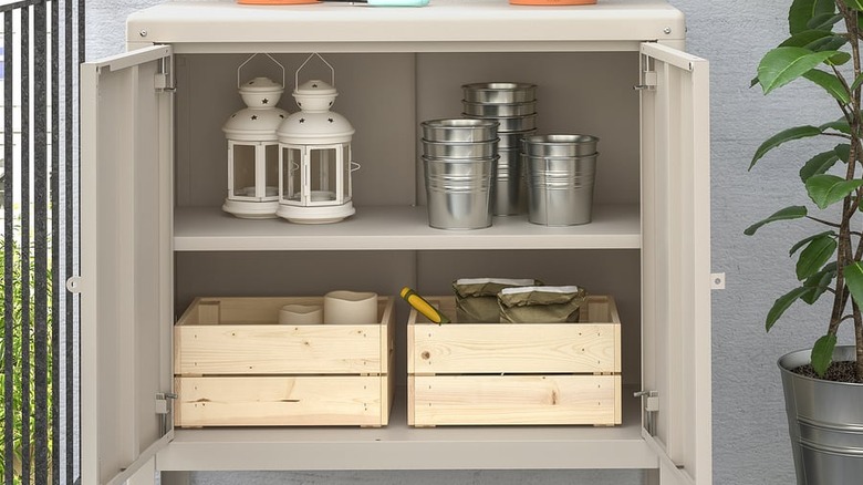Open KOLBJÖRN cabinet with lanterns, plant pots, and wooden storage crates on shelves.