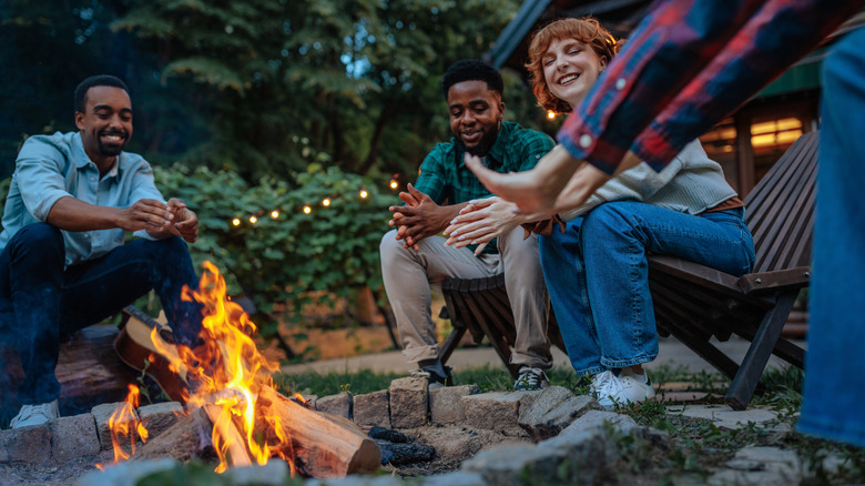 Friends gathered around a fire pit outdoors in a backyard
