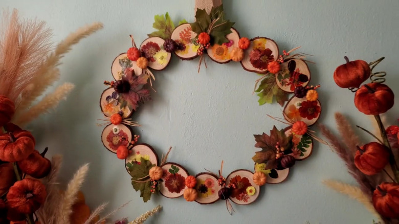 A pumpkin-shaped wreath made of craft rounds with fall-themed accents