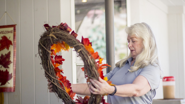 Woman looking at a fall wreath in her hands