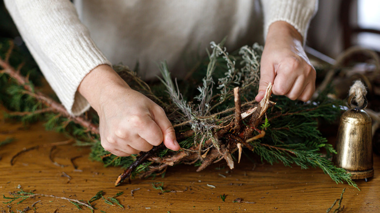 Hands crafting a wreath with bells