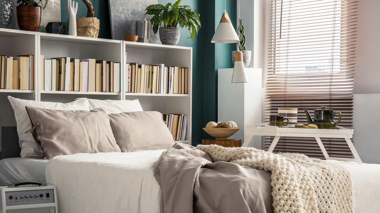 A cozy bed with bookcase headboard and decor on top