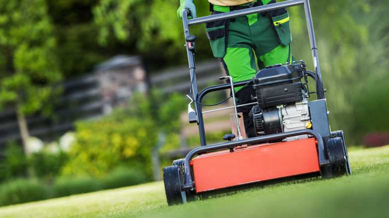 A man using an aerating machine on a lawn