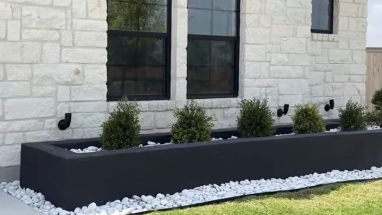 Concrete block planter covered with concrete and painted black