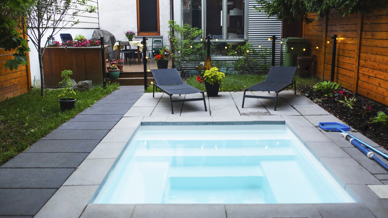 A cocktail pool with built-in seating in a small backyard.