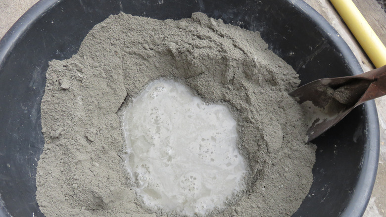 Mixing cement in a bucket to make mortar