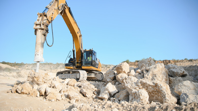 Excavator machine breaking up limestone boulders