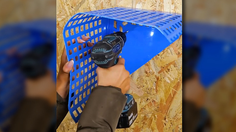 Person mounting a DIY tool organizer made from plastic basket