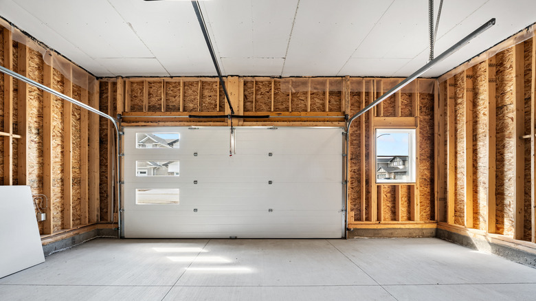 An empty garage with a white door and window to the side.