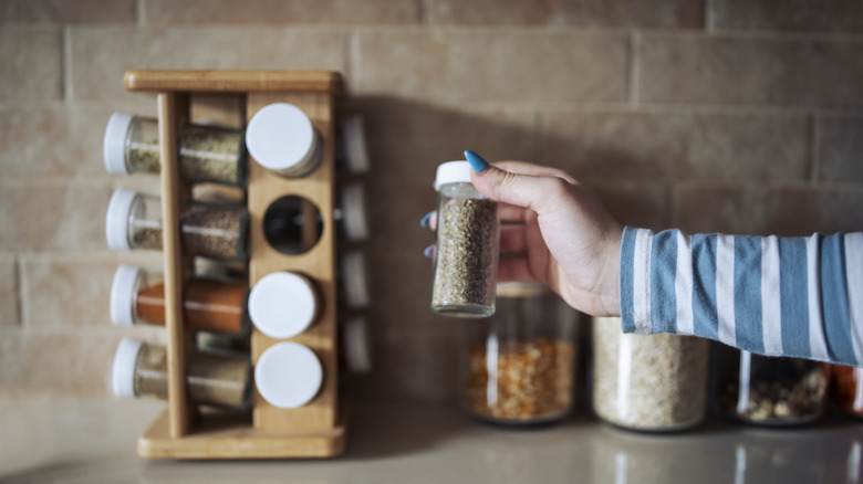 Hand holding jar of spices on kitchen counter