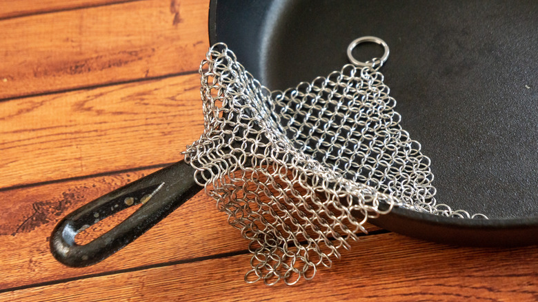 A chain mail sponge sits on a cast iron pan