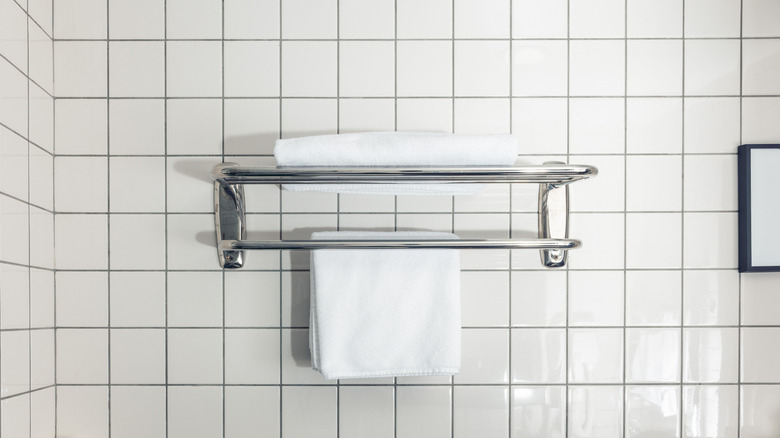 A modern tile bathroom with a towel rack that has towels hanging from it.