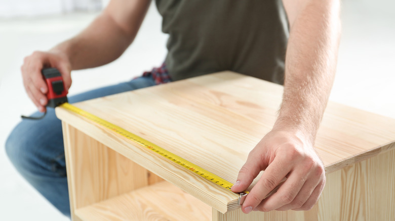 man measuring wooden drawer