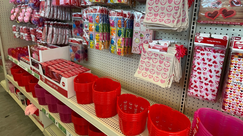 A series of little hearts, a house key, and a house with a heart window on a counter with a case with a plant carrying little hearts