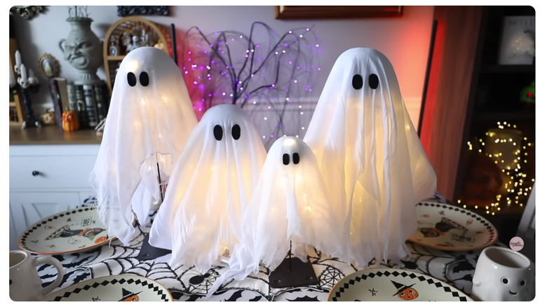 Halloween ghost lamps sitting on a Halloween-themed table