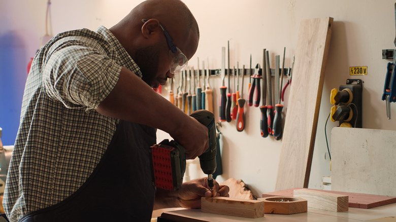 Man drilling into small piece of wood in workshop