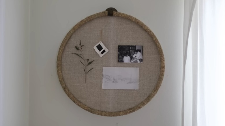 A round, brown pinboard hangs on a wall