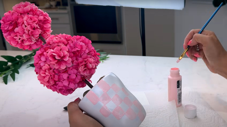 Close up of person painting pink squares on flower pot