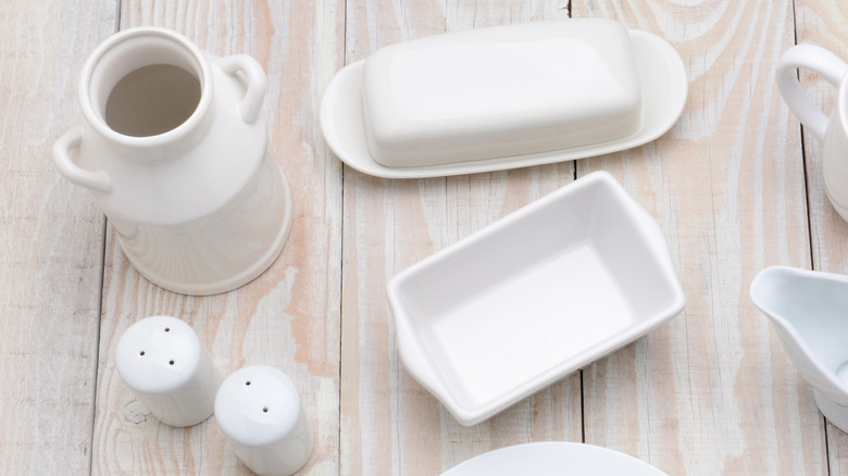 White ceramic dishware sits on a light wood table.