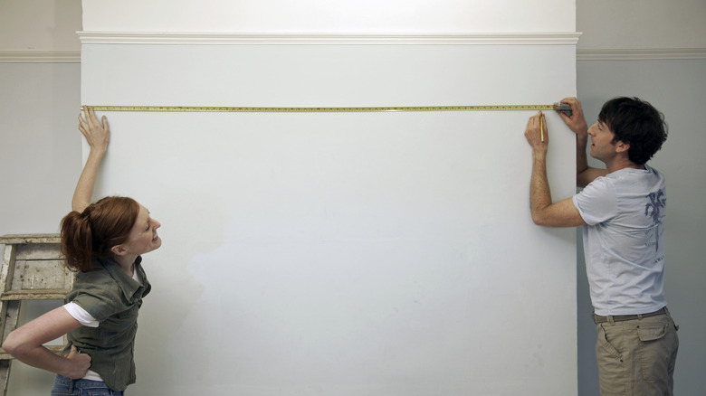 A couple measuring a wall