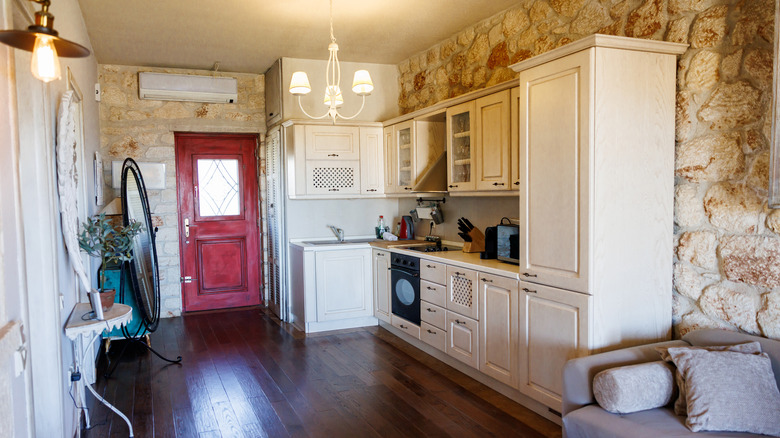 small rustic kitchen with stone wall and red front door