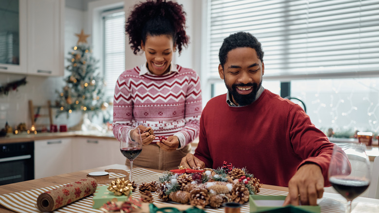 Happy couple making DIY Christmas wreath on kitchen island