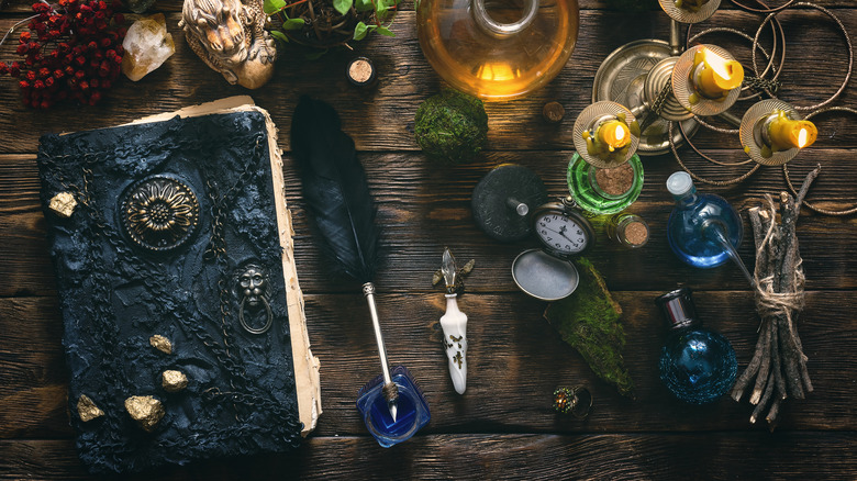 A spellbook rests on a wooden table with other witch-inspired decor items.