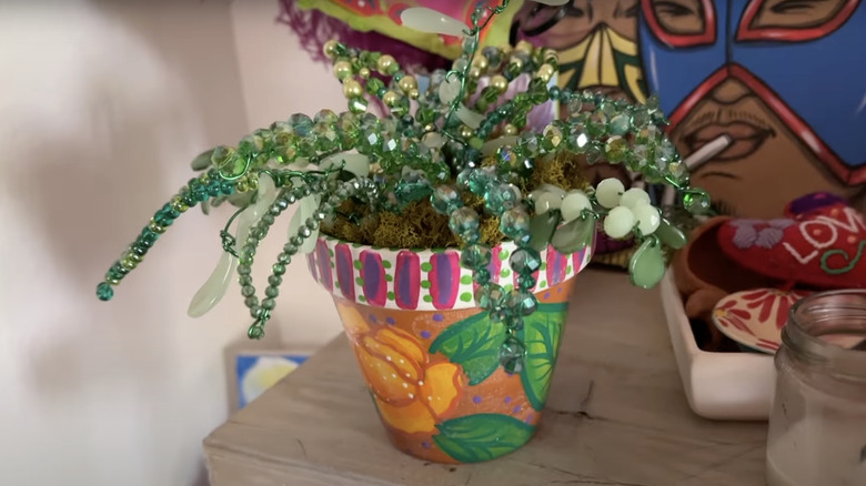 A bead plant in a pot sits on the top of a dresser as indoor decor.