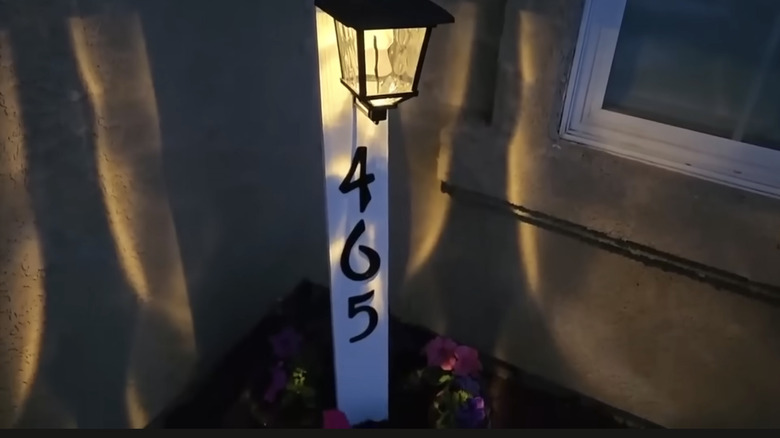 The glowing solar planter and house sign lit up at night
