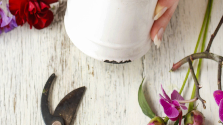 Close-up of hands putting flowers in a white can