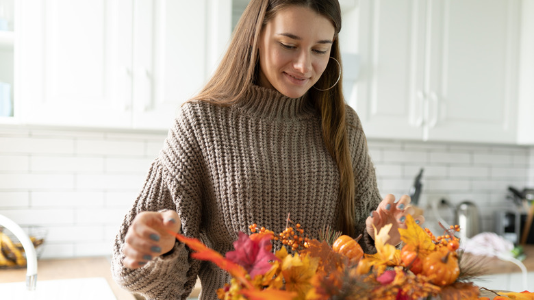 woman with fall leaves and pumpkins ready to craft