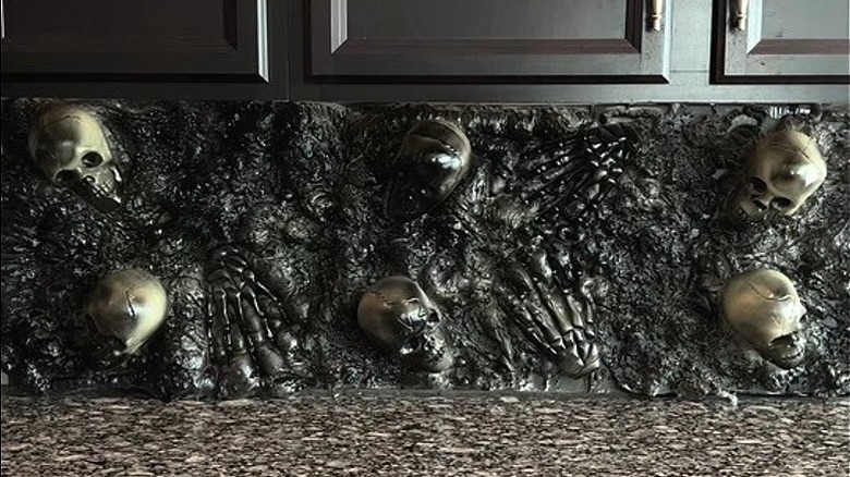 A black backsplash made out of spray foam with skulls and skeleton hands