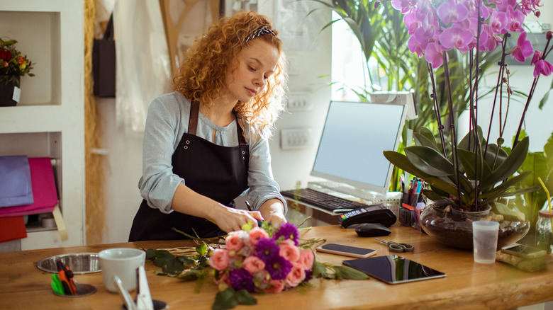 woman with an apron working with flowers in a crafty environment