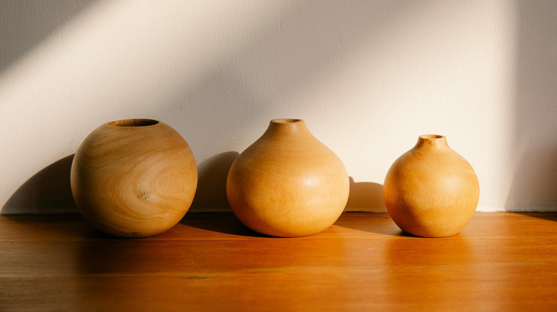 Three wooden vases lined up against a wall