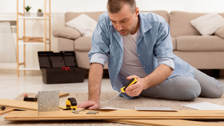 Person staring at wood boards and screws