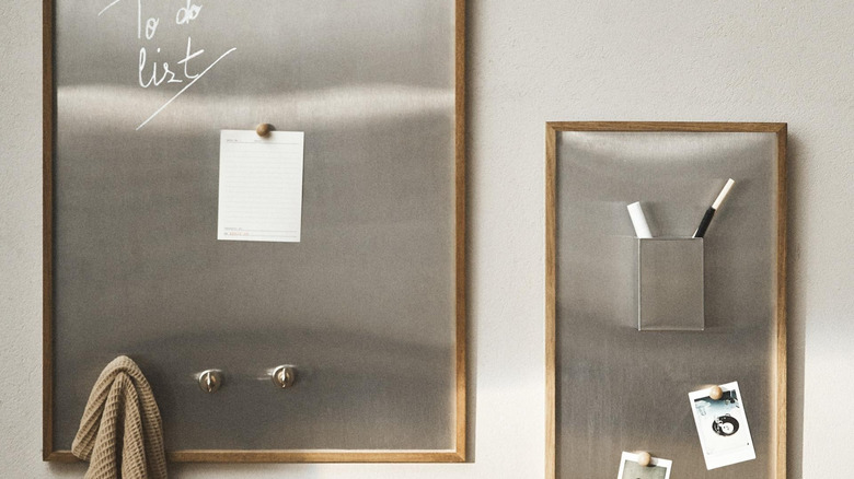 Two wood-framed stainless steel boards from Zara with magnets, notes, handwriting, a caddy, and hooks.