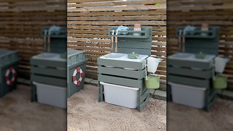 A cute mud kitchen created with IKEA products in a sandy backyard.