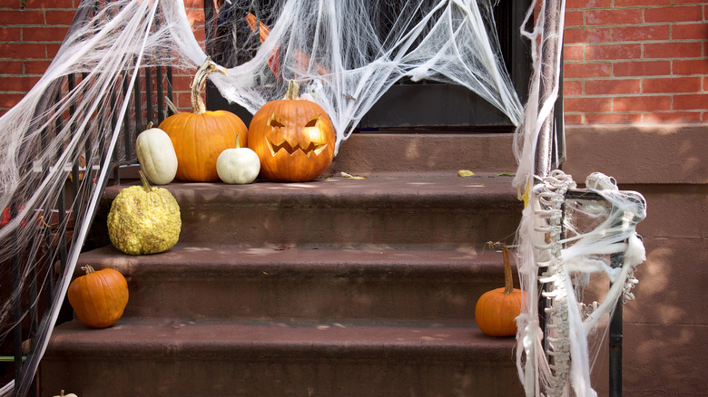 Porch decorated with pumpkins, skeletons, and spiderwebs for Halloween
