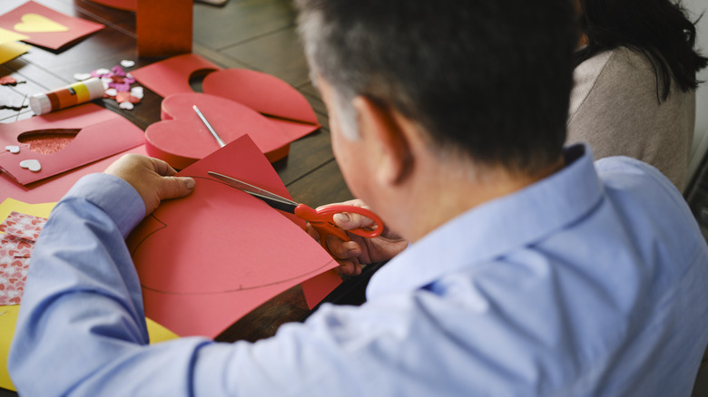 man cutting heart out of paper