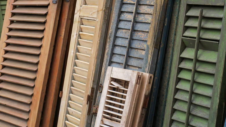 A series of old shutters in various sizes, colors, and states of decay
