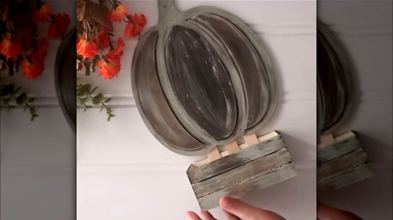 Person assembling a fall planter with Dollar Tree decor pieces