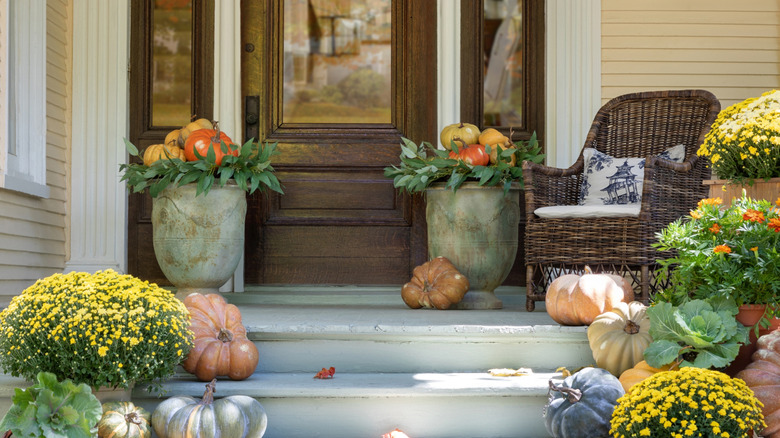 A front porch decorated with gourds and fall foliage
