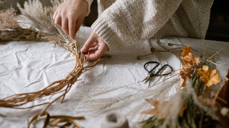 Close up of a person making a fall wreath with foraged items.