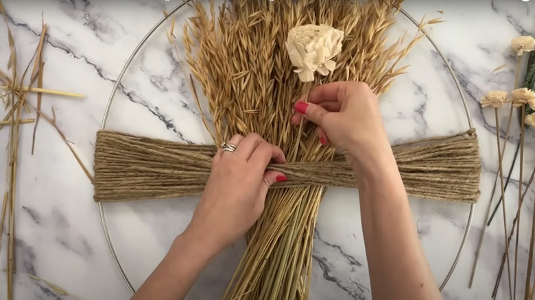 Close up of person placing dried flowers in DIY wreath