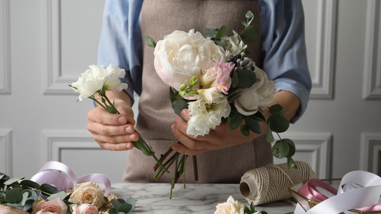 Person holding flowers with rope and ribbons on a table