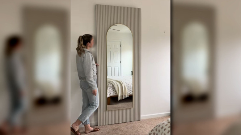 A screenshot of a woman in front of her DIY fluted door with a mirror